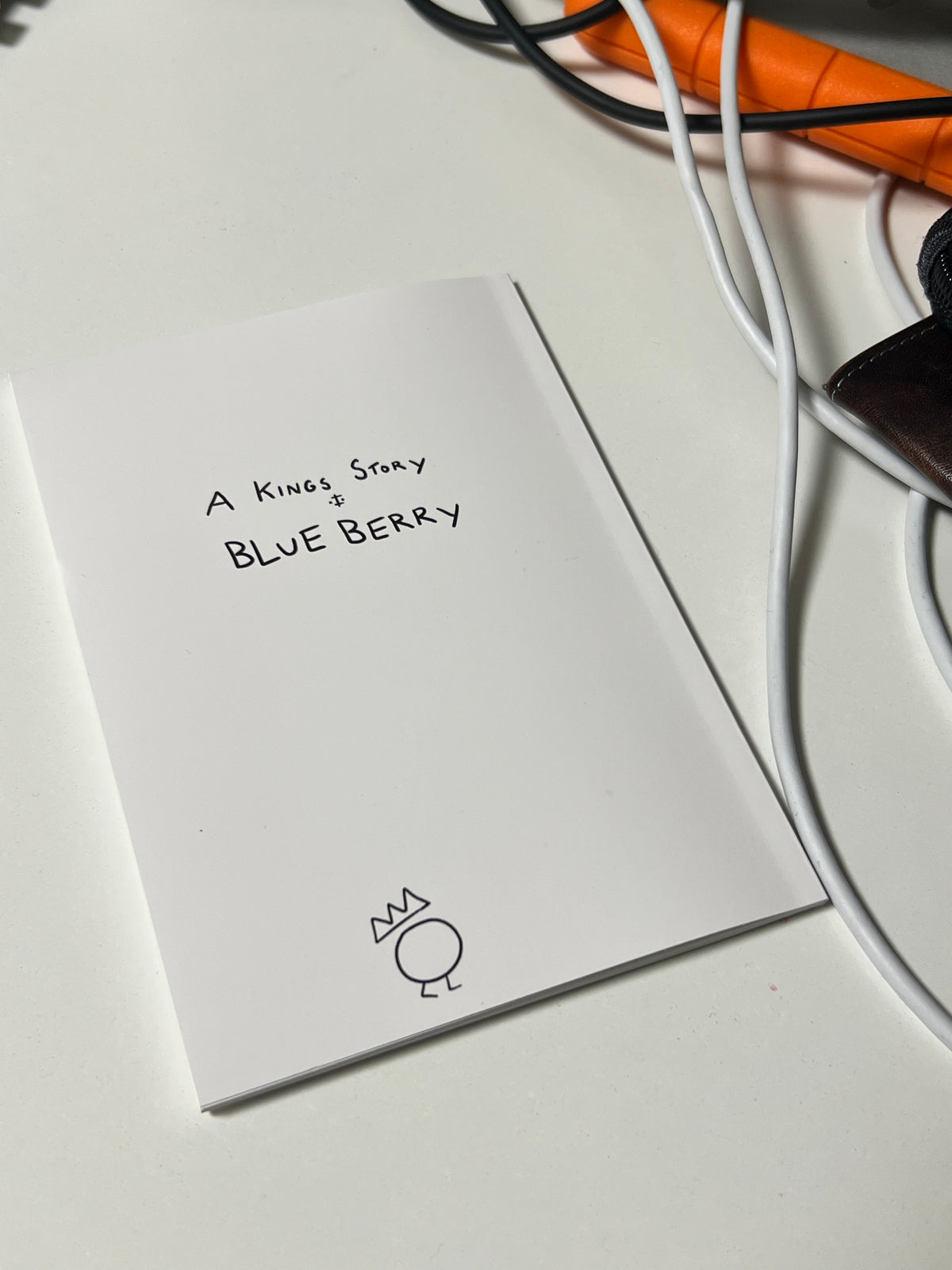 Product packaging with text 'A Kings Story - BlueBerry' on a white background with wires nearby